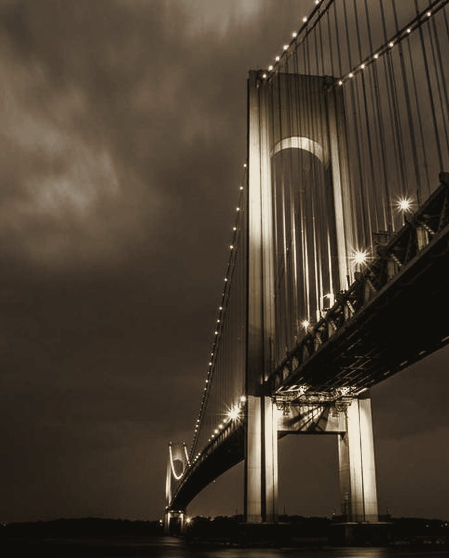 The taut cables of a slender pedestrian span seen against pale sky.